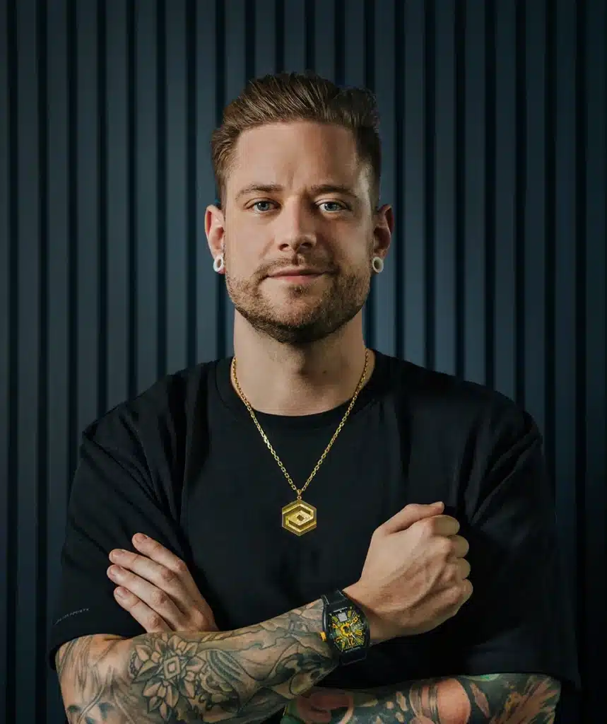 Ist Florian Sonderhausen seriös? Kosten, Erfahrungen & alles über die Trading-Ausbildung (2026) florian sonderhausen vor einem grauen hintergrund mit gekreuzten armen