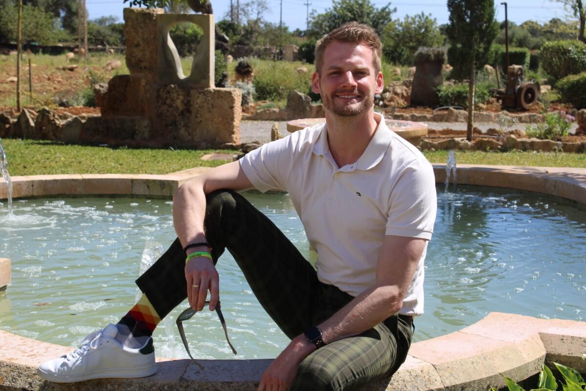 optionshandel coach markus herfert sitzt auf mauer vor einem brunnen