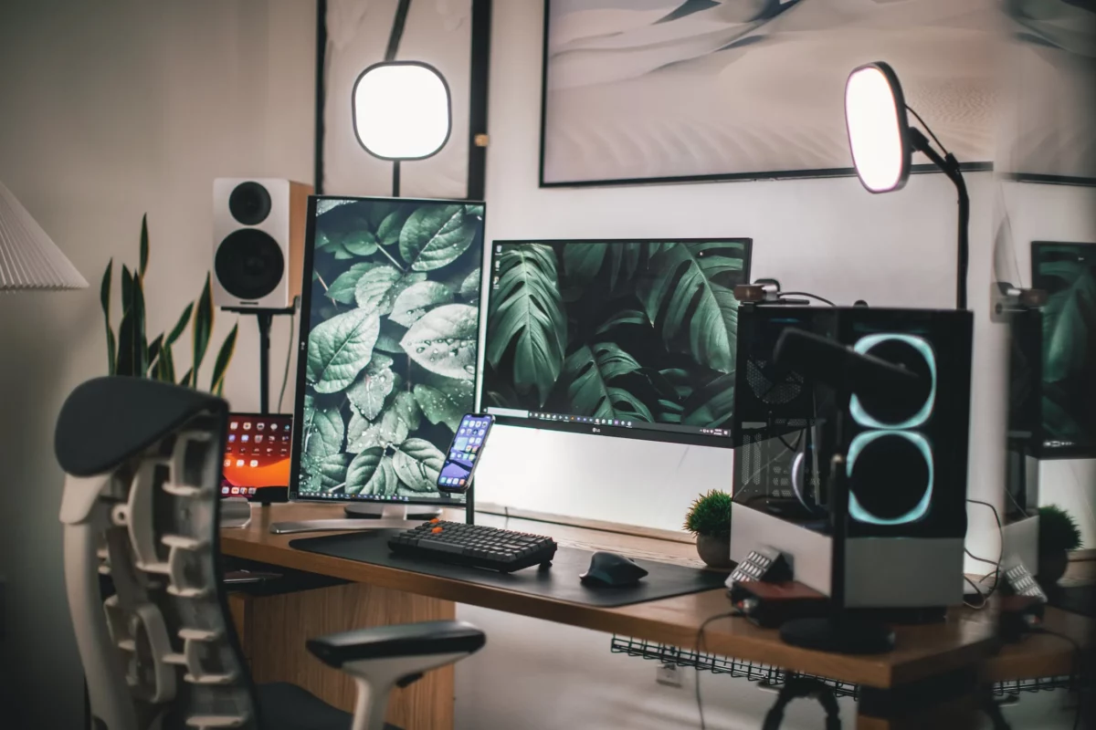 Das Bild zeigt ein Trading Setup mit drei Bildschirmen und Smartphone. 